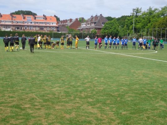 Beide teams staan klaar voor de aftrap met scheidsrechter Oskam in het midden